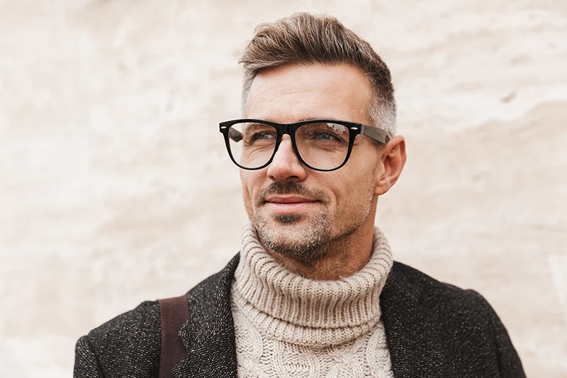 eyeglass-lenses a man with glasses wearing a sweater and coat outside